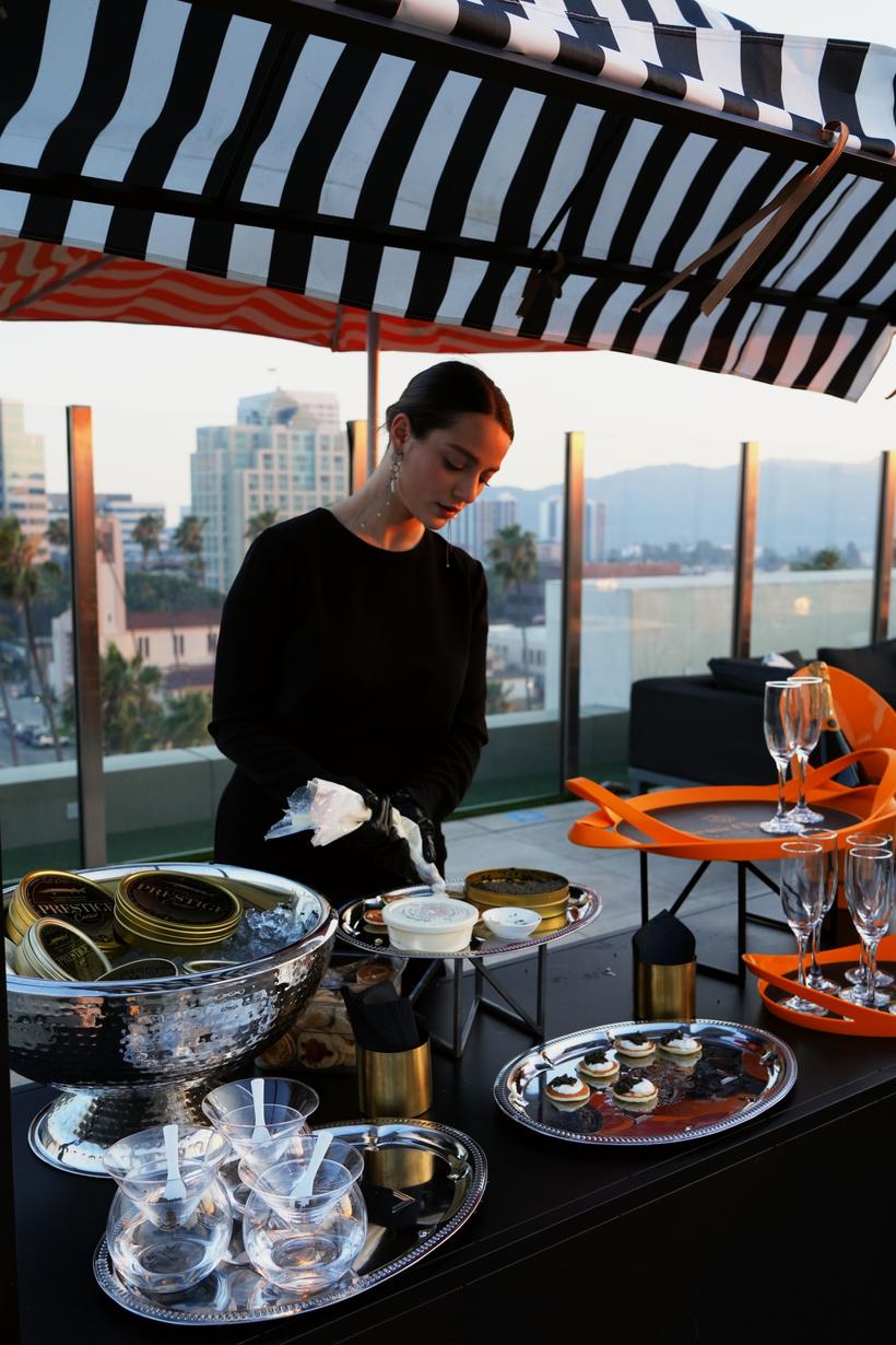 A server preparing caviar on the rooftop with the skyline behind